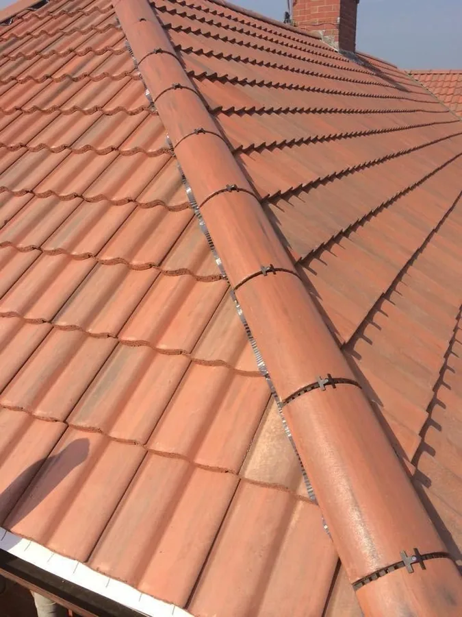 Close detail of a mechanically fixed dry ridge and hip on a new terracotta pantile roof