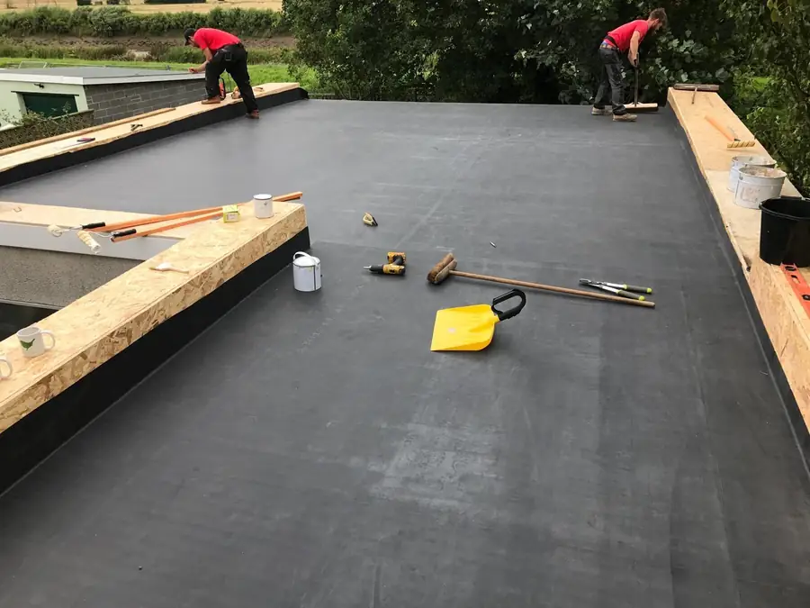 Two roofers bonding an EPDM membrane on a large flat roof