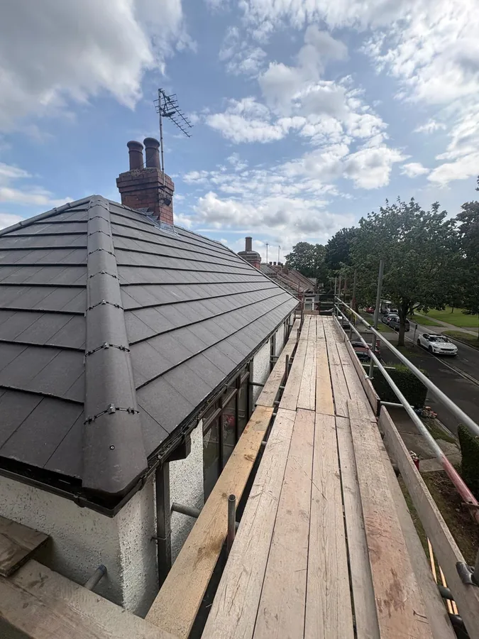 New grey flat tile roof in Beverley looking along the finished ridge, chimney stack and scaffold run