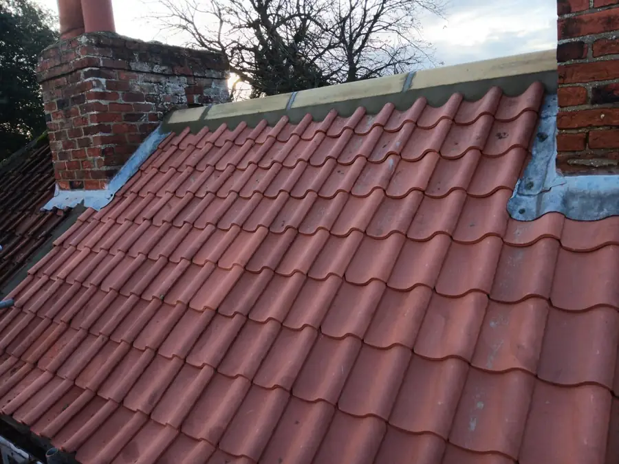 Terracotta pantile roof with new lead flashing to a brick abutment wall