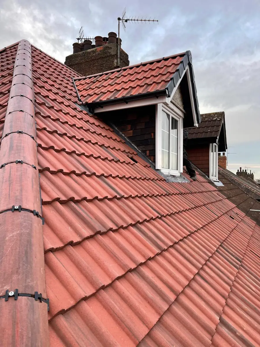 Completed terracotta pantile roof with two dormer windows and a chimney