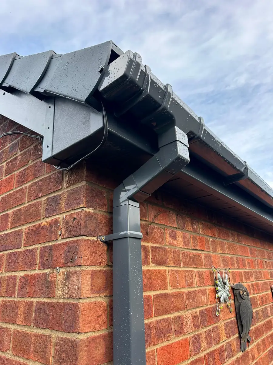 Anthracite fascia, gutter and downpipe fitted to a red brick corner