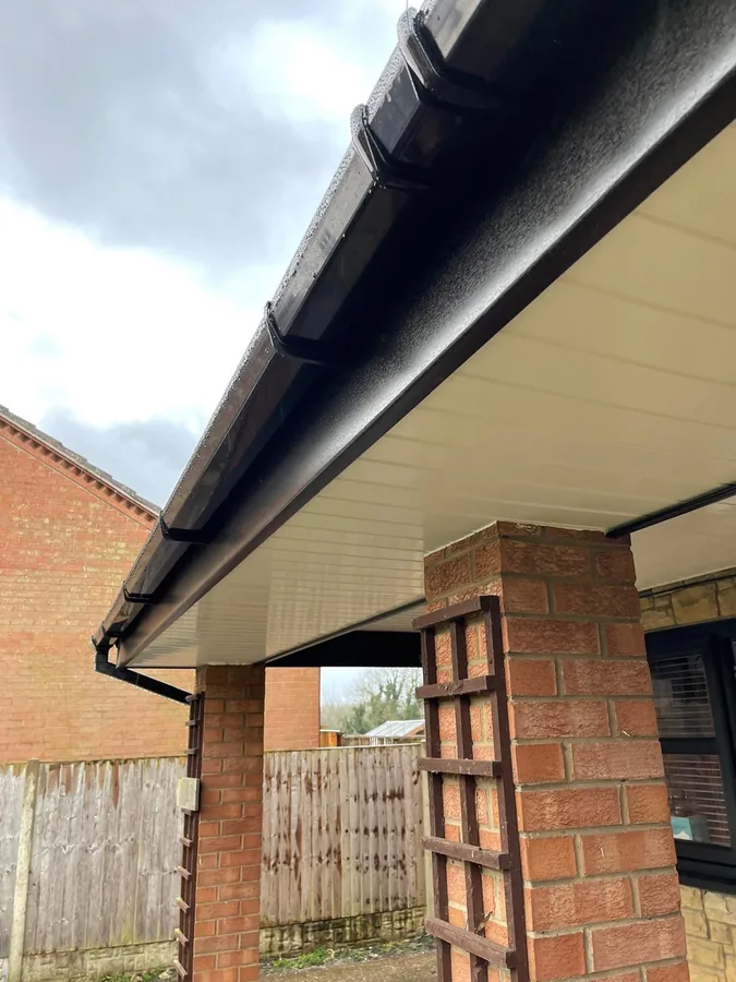 Black uPVC fascia and half round guttering with a cream soffit over a brick pillared porch