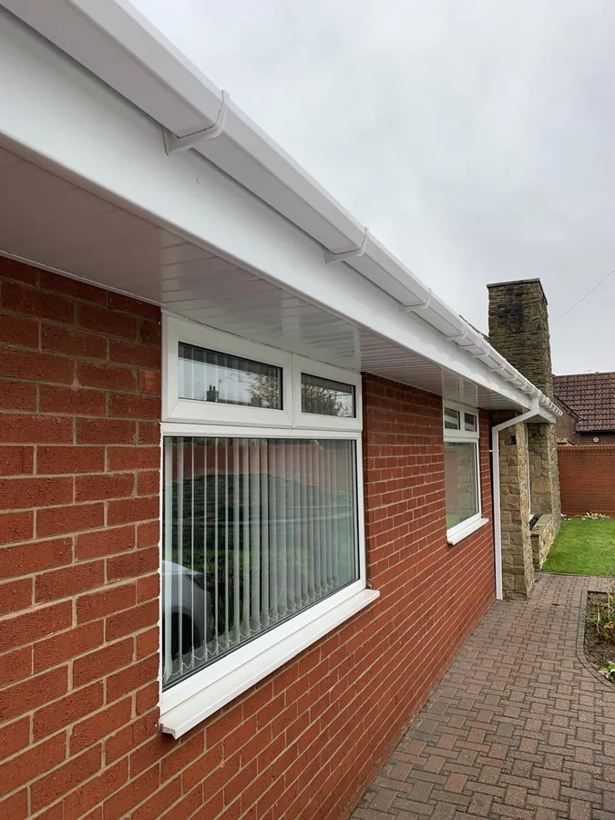 New white fascia, soffit and round guttering running along the side of a red brick bungalow