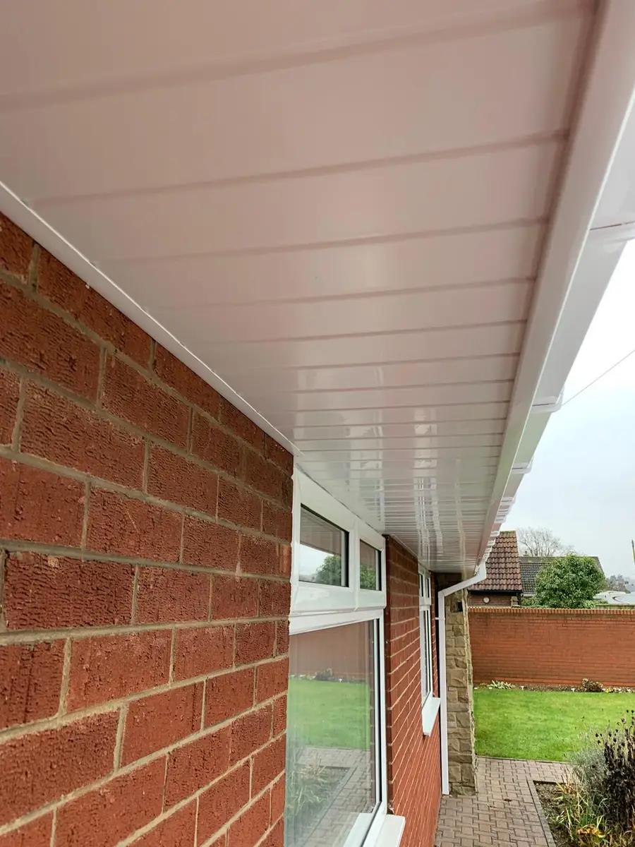 Long run of new white soffit and guttering along the side of a brick property