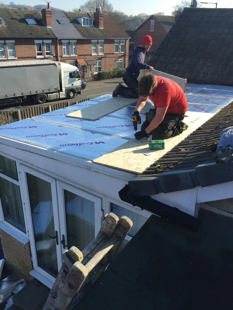 Insulation boards being fixed to a flat roof deck during a warm roof build up